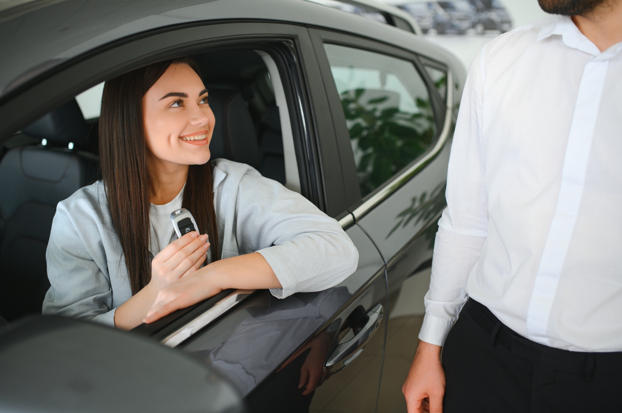Car dealer giving key to new car owner